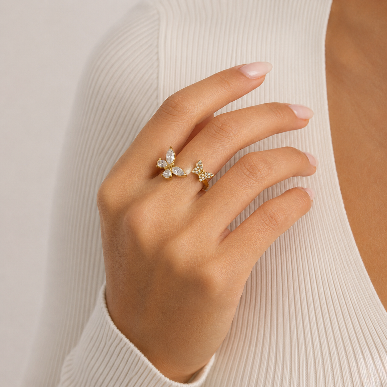 Butterfly bypass ring in gold with pearl and crystal details on a hand wearing a white ribbed top