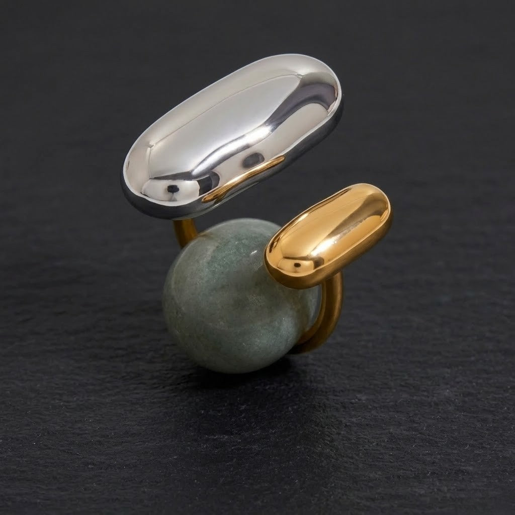 Tonal Fusion Ring: gold and silver accents with a green stone centerpiece on a dark background