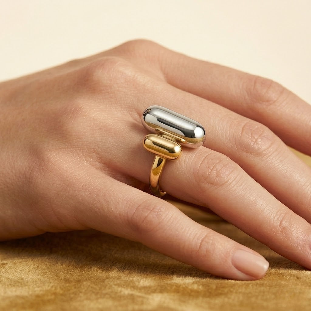 Tonal Fusion Ring in silver and gold on hand, showcasing modern dual-metal capsule design on soft fabric background.