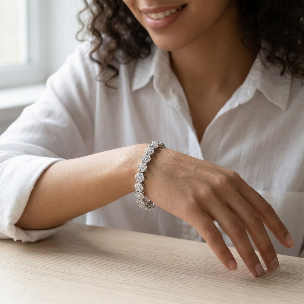 Sterling silver tennis bracelet with floral cluster cubic Moissanite links worn on wrist resting on table by model wearing a white button-up shirt by J.Collins

