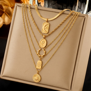 Gold layered necklaces with celestial medallion pendants displayed on a beige stand