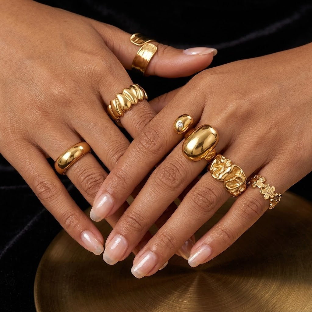 Gold textured coil ring on model's hand, showcasing multiple gold rings against a dark background.