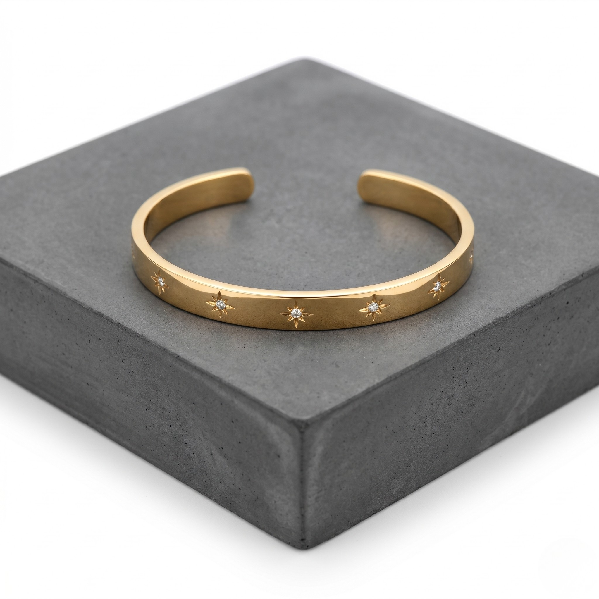 Gold cuff bracelet engraved with starburst design on a gray background