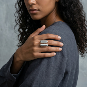 Woman wearing silver twin bar ring on her hand, styled with a dark gray sleeve in a lifestyle context