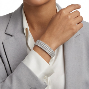 Wide multi-row sterling silver tennis bracelet encrusted with cubic Moissanite  crystals worn on wrist by model Tiffany wearing a grey blazer over a white shirt by J.Collins
