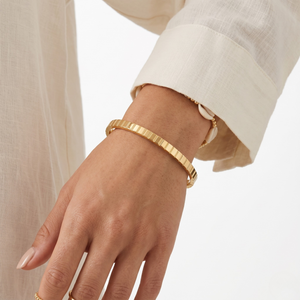 Gold plaid Marcello bangle worn on a model's wrist with a cream blouse.