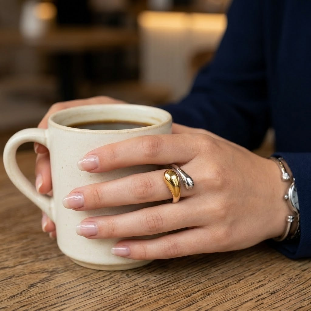 Bicolor Vertex Ring on hand holding a coffee mug, showcasing polished gold and silver tones in a modern style.
