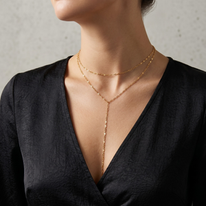 Gold Y-link chain necklace with delicate double chain detail, worn by a person in a black V-neck top.