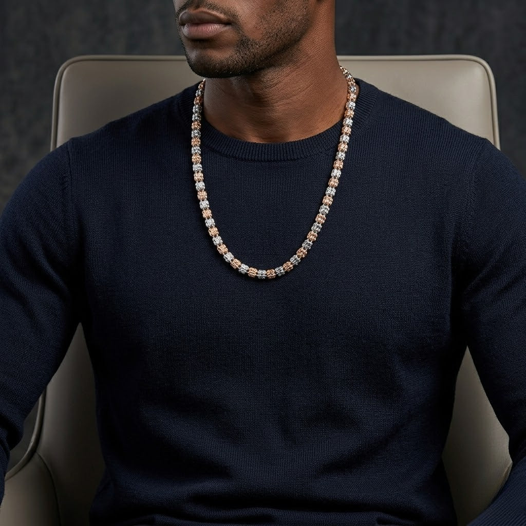 Man wearing Italian two-tone bead necklace with gold and silver accents, seated in a chair wearing a navy sweater