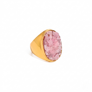 Gold ring with a pink crystal inlay, bold and modern design on a plain background.