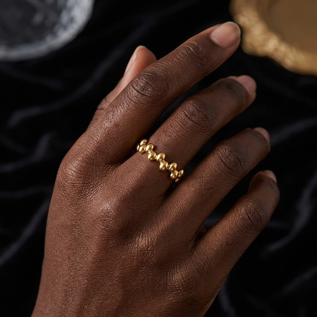 Oracle Beaded Ring in gold on hand with black velvet background, elegant and modern style