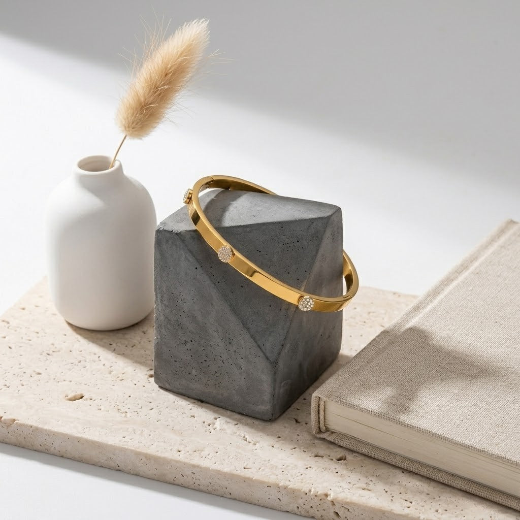 Gold Horizon Beam Bracelet on geometric concrete stand with book and vase for elegant display