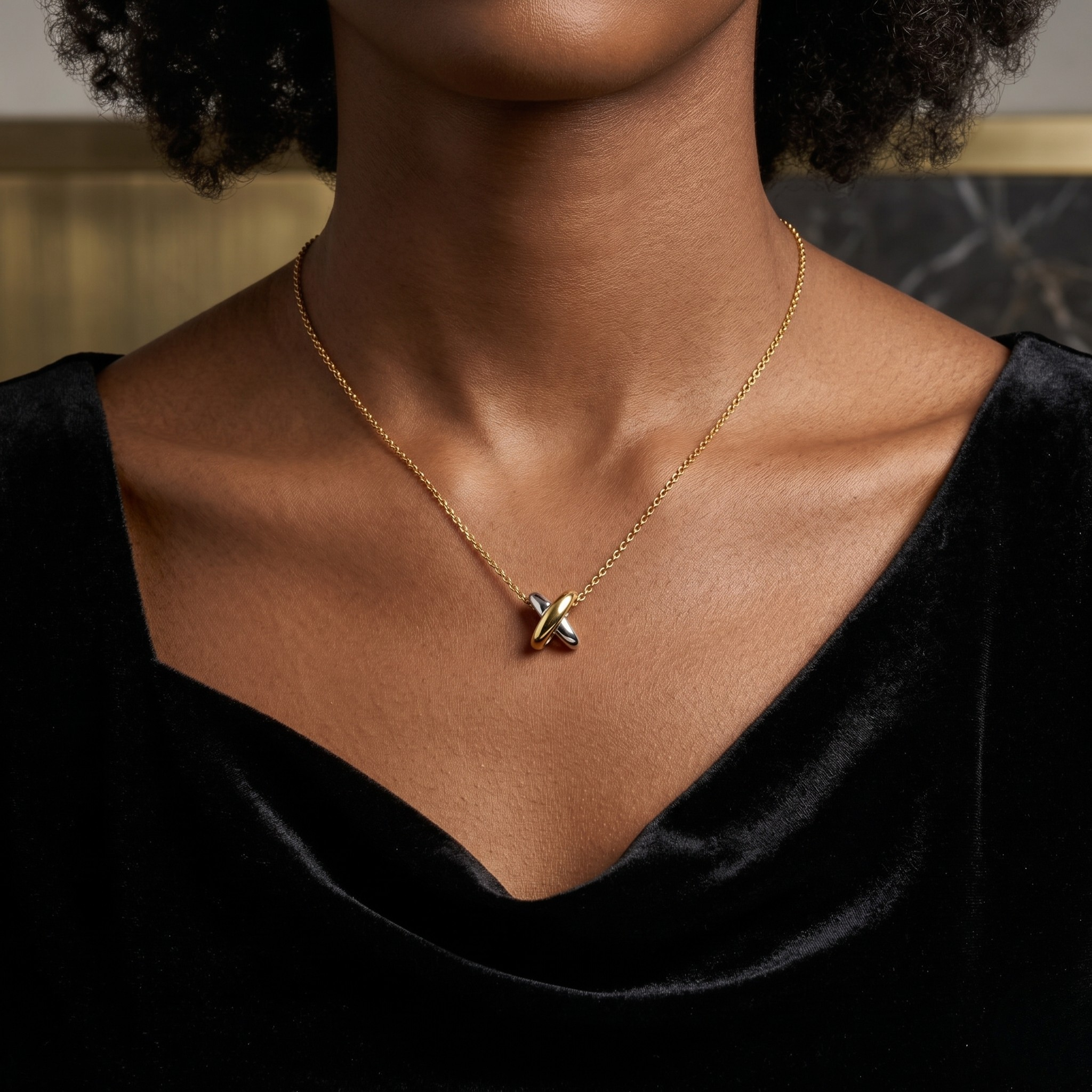 Gold mirror junction charm pendant on black velvet worn by model with short curly hair