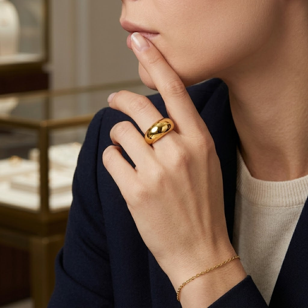 Gold dome ring worn on woman's finger with blue blazer, jewelry store setting in background