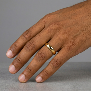 Hand wearing a gold ring on a gray background