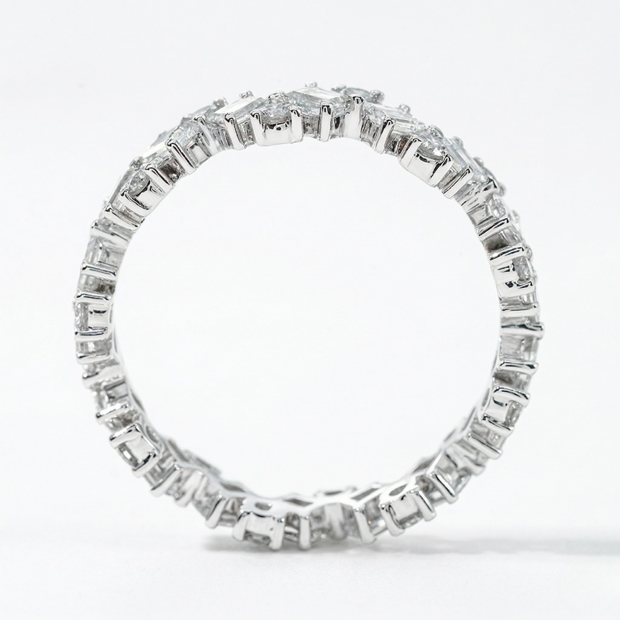 18K white gold eternity band with lab diamonds in a prong setting, viewed from the side against a white background