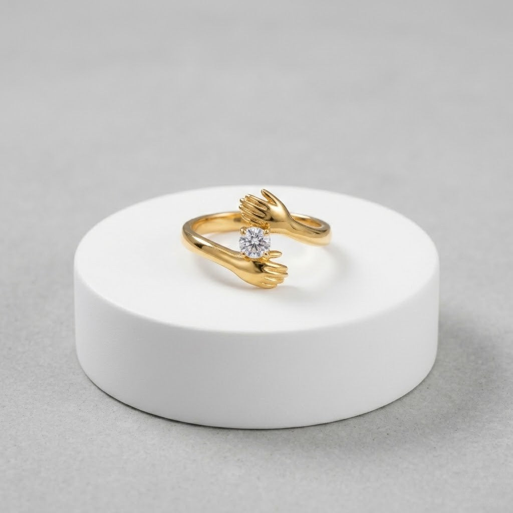 Gold ring with embracing hands design and central diamond.