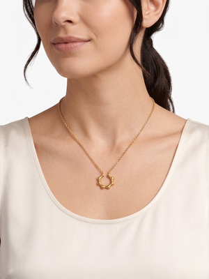 Gold star-shaped pendant necklace on woman wearing a white top, side profile view