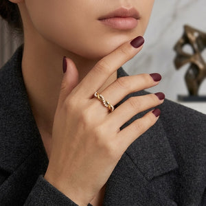 Model wearing a gold spiral pearl ring with maroon nails in a sophisticated setting.