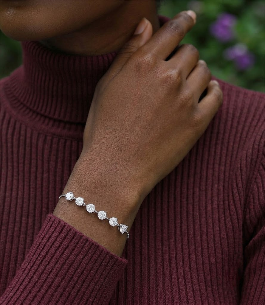 Sterling silver adjustable bolo slider bracelet featuring round cubic Moissanite stone stations worn on wrist by model  wearing a maroon ribbed turtleneck sweater by J.Collins
