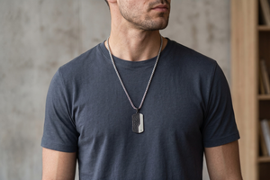Man wearing a dark blue t-shirt and a necklace with a pendant against a neutral background-J.Collins Jewelry
