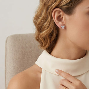 Close-up of a person wearing butterfly earrings with a neutral background. J.Collins Jewelry 