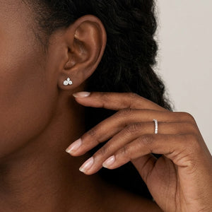Model  wearing a delicate silver three-stone cluster diamond stud earring and a matching eternity band ring | J.Collins Jewelry
