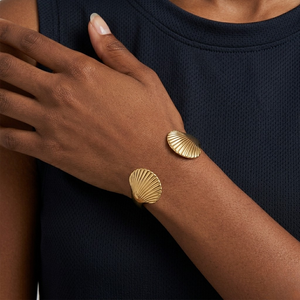 Model  wearing a gold open cuff bracelet featuring detailed seashell motifs at each end | J.Collins Jewelry