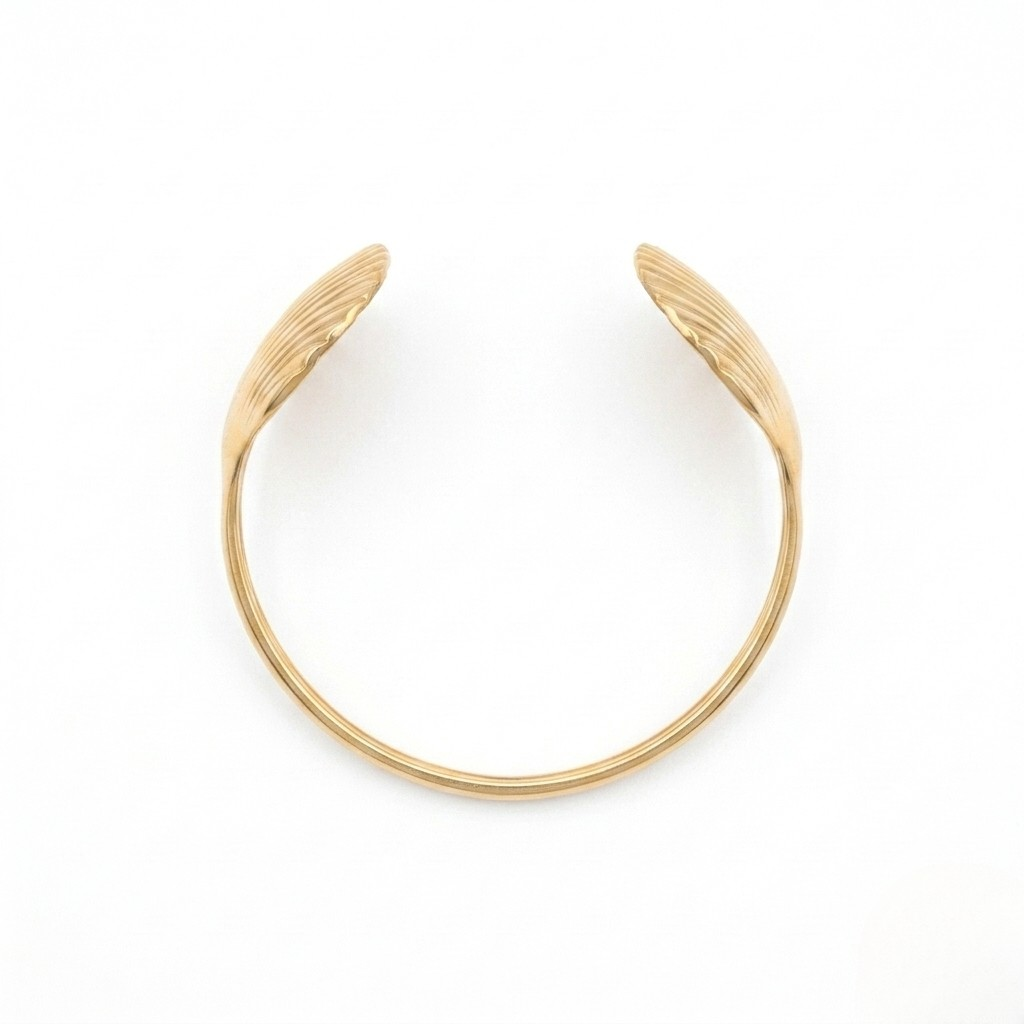 Overhead view of a gold open cuff bracelet with ribbed seashell ends isolated on a white background | J.Collins Jewelry