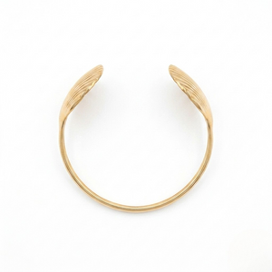 Overhead view of a gold open cuff bracelet with ribbed seashell ends isolated on a white background | J.Collins Jewelry