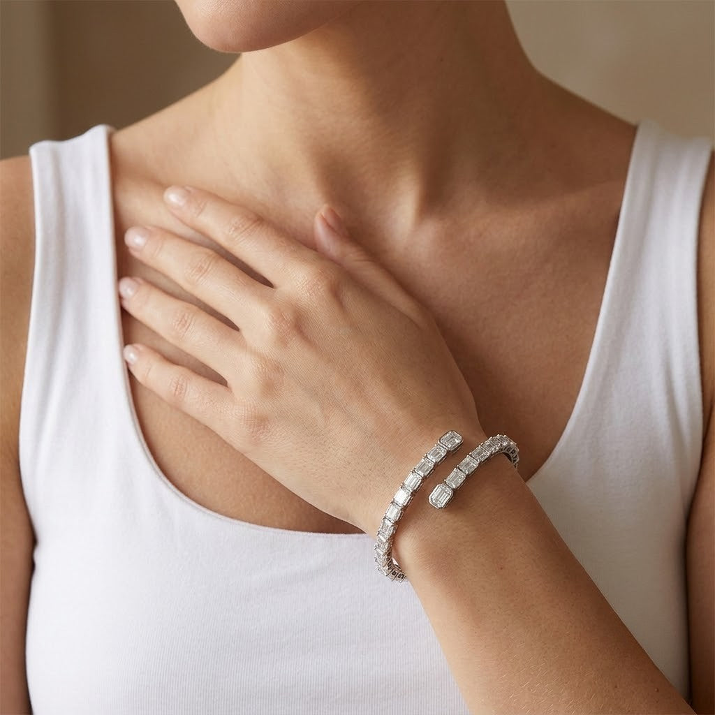 Flexible sterling silver open wrap tennis bracelet set with emerald-cut cubic Moissanite crystals worn on wrist by model Tiffany wearing a white tank top by J.Collins
