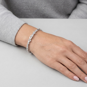 Hand wearing a silver bracelet on a light gray background-J.Collins Jewelry