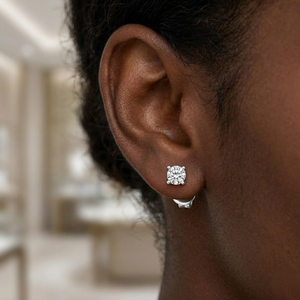 Close-up of a person wearing a diamond stud earring with a blurred indoor background - Diamond Earrings Basket 0.144ct - J Collins Jewelry 