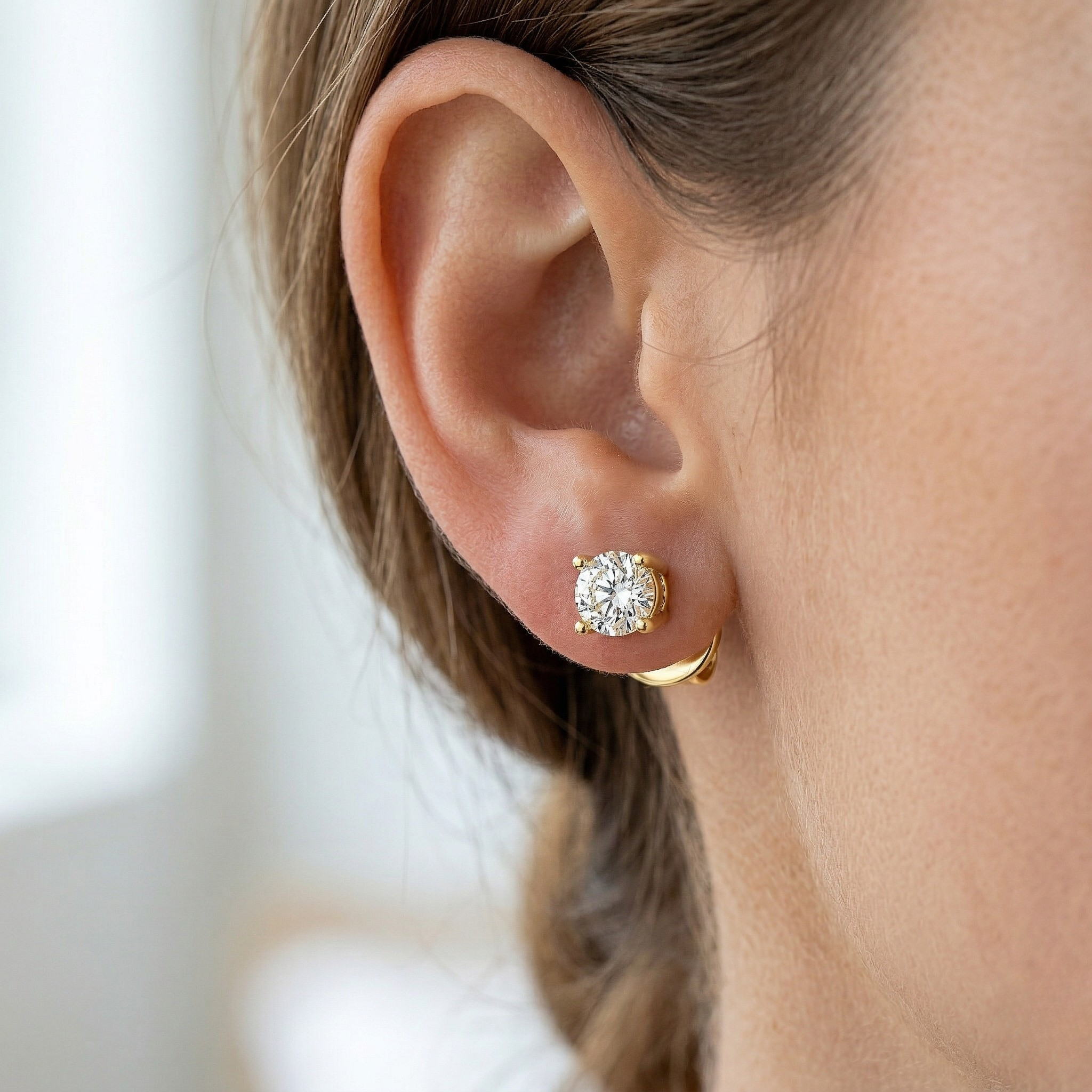 Close-up of a person wearing gold earrings with a blurred background - Diamond Earrings Basket 0.283ct - J. Collins Jewelry 