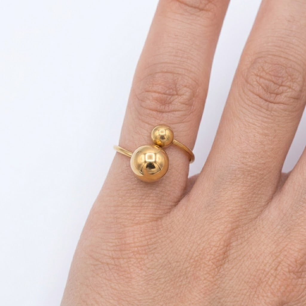 Close-up view of a chic gold bypass ring with two polished statement spheres worn on a hand | J.Collins Jewelry