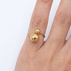 Close-up view of a chic gold bypass ring with two polished statement spheres worn on a hand | J.Collins Jewelry