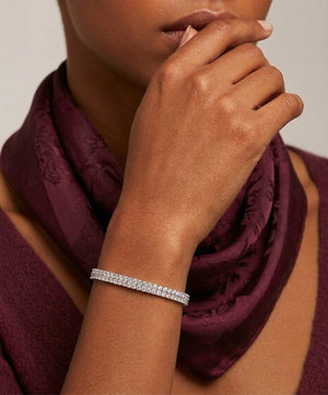 Double-row sterling silver tennis bracelet set with round cubic Moissanite crystals worn on wrist by model  wearing a burgundy scarf and top by J.Collins
