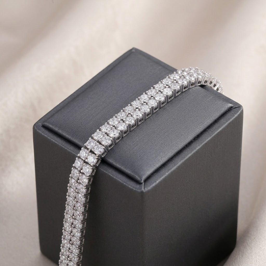 Double-row sterling silver tennis bracelet set with round cubic Moissanite crystals draped over a dark grey jewelry box by J.Collins
