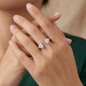 
Sterling silver open adjustable cuff ring featuring dual heart-shaped cubic zirconia gemstones worn on hand by model wearing a dark green top by J.Collins
