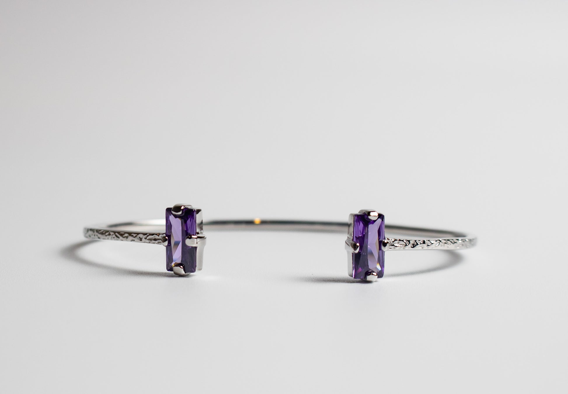 Silver bracelet with purple gemstones on a light gray background - Duara Cuff Bracelet - JCollins Jewelry  
