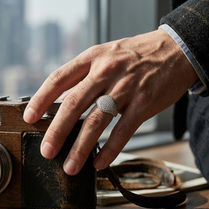 Men's silver pavé dome signet ring worn on hand resting on vintage camera by J.Collins⁠
