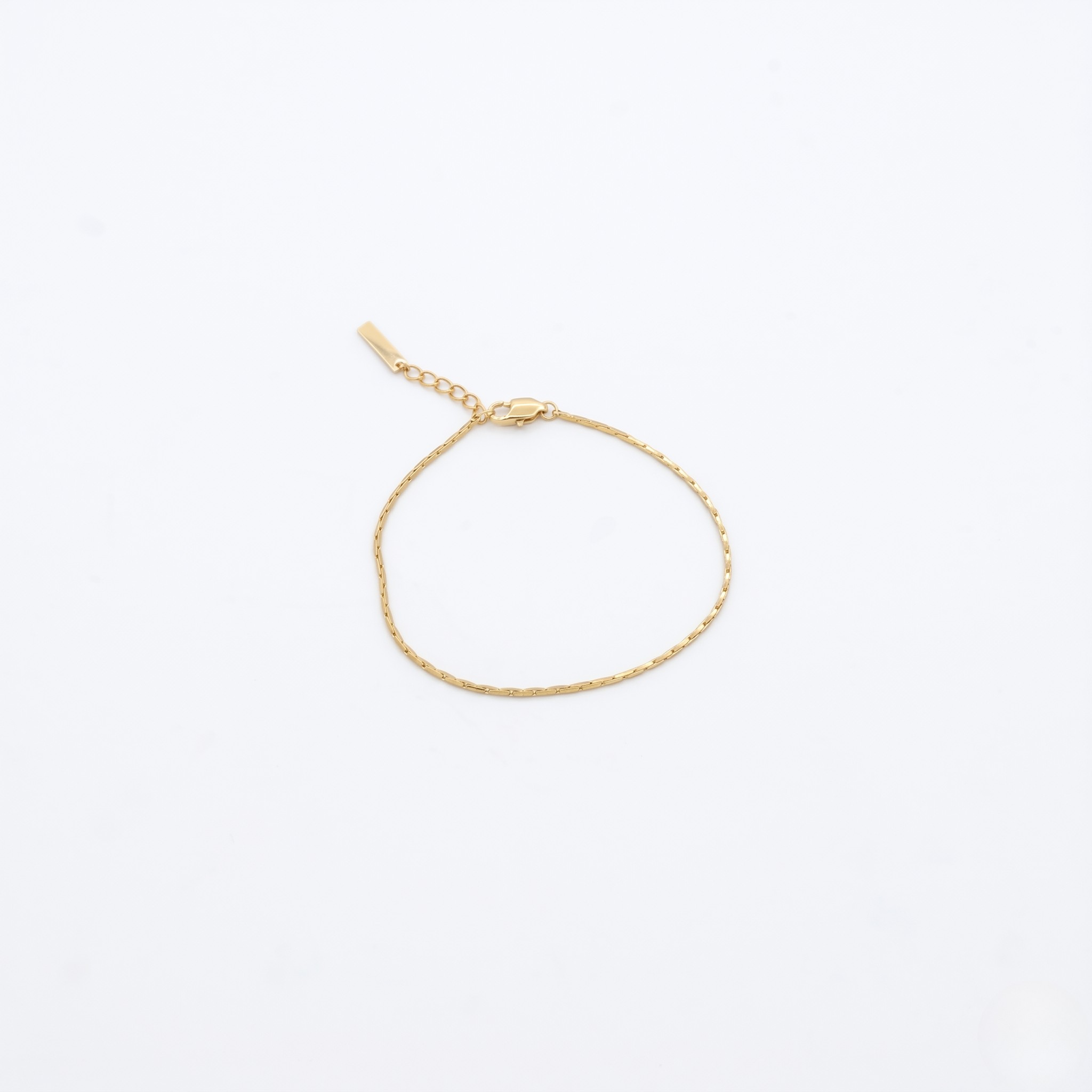 Gold bracelet on a light beige background- J.Collins Jewelry