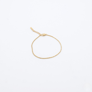 Gold bracelet on a light beige background- J.Collins Jewelry