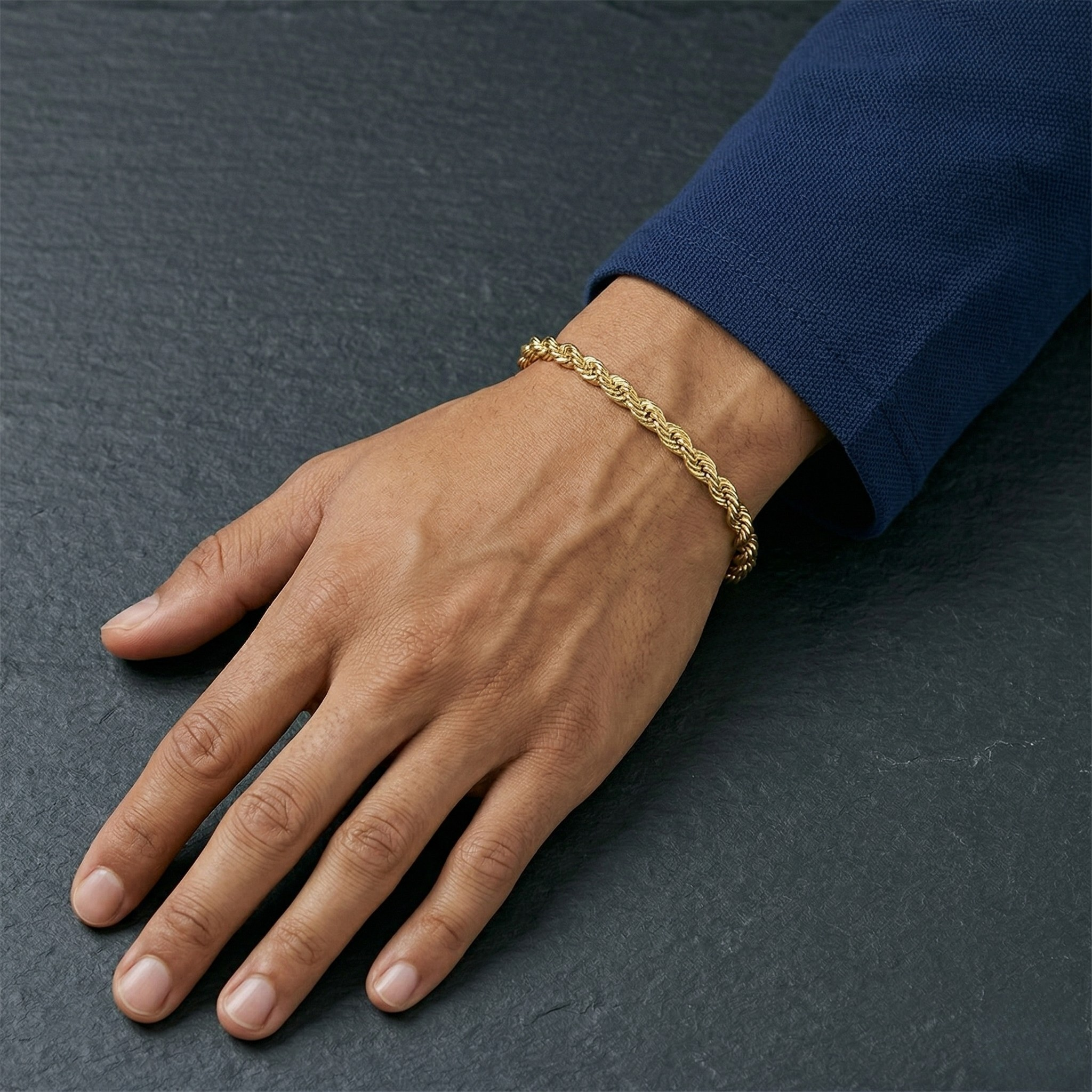 Hand wearing a gold rope bracelet on a dark surface- Essential Rope Bracelet 5mm (Gold ) by J.Collins Jewelry 