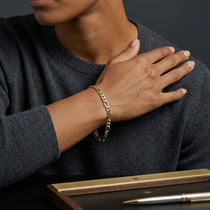 Person wearing a gold chain bracelet with a dark sweater and wooden box in the foreground-J.Collins Jewery