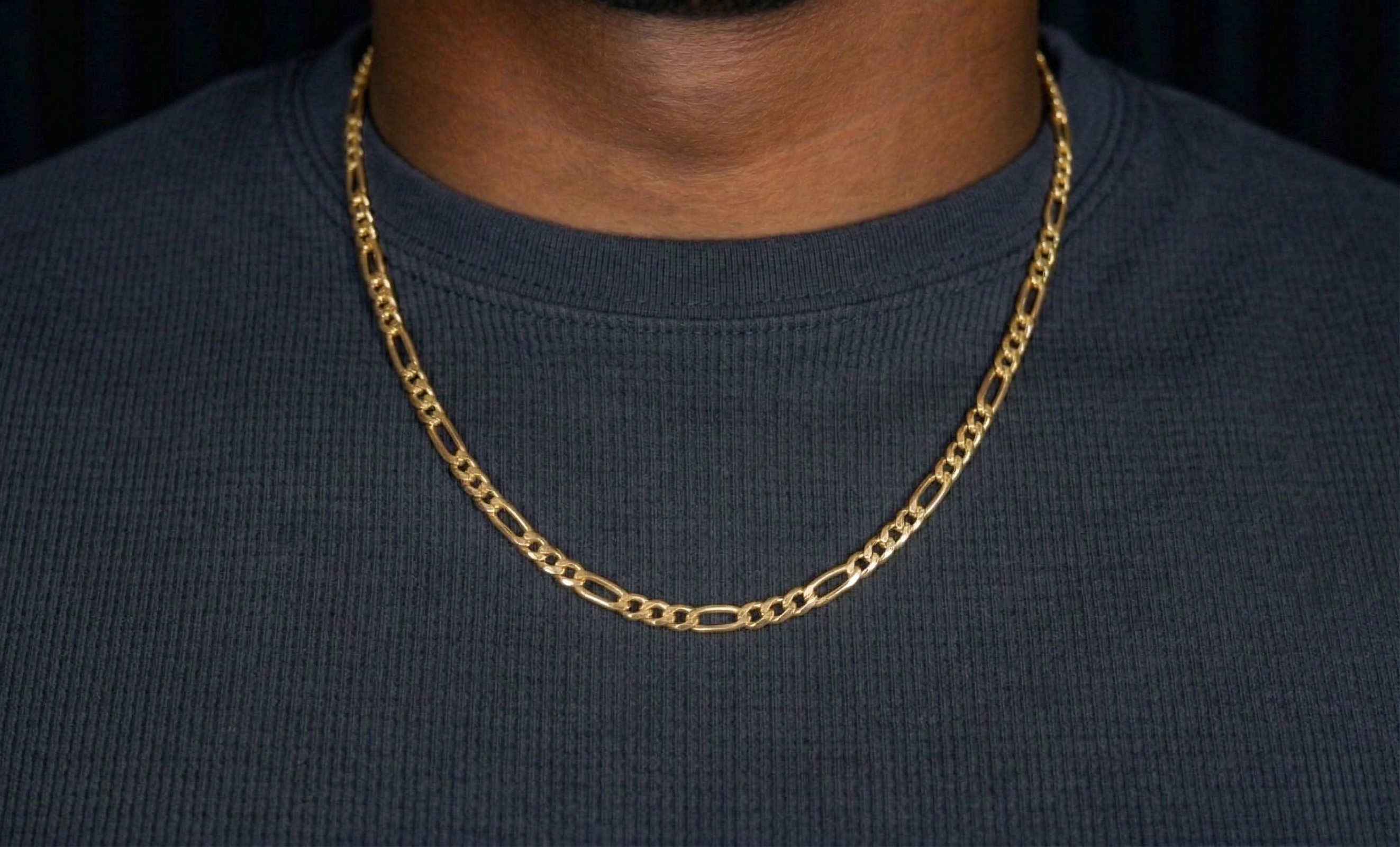 Gold chain necklace worn by a person on a dark background-J.Collins Jewelry