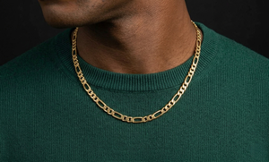 Gold chain necklace worn by a person in a green sweater against a black background-J.Collins Jewelry