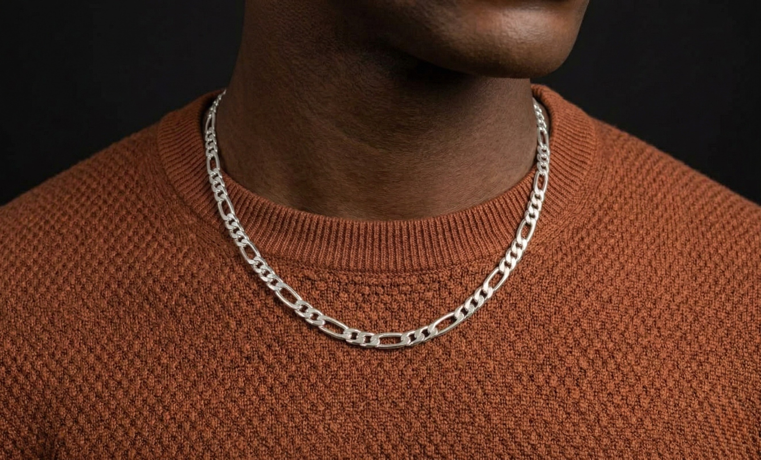 Silver chain necklace on a person wearing a brown sweater against a black background-J.Collins Jewelry
