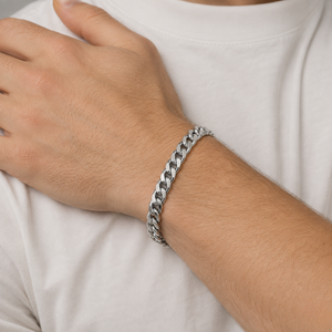 A close-up of a person's wrist wearing a thick silver Franco link chain bracelet, shown against a white t-shirt - J.Collins Jewelry