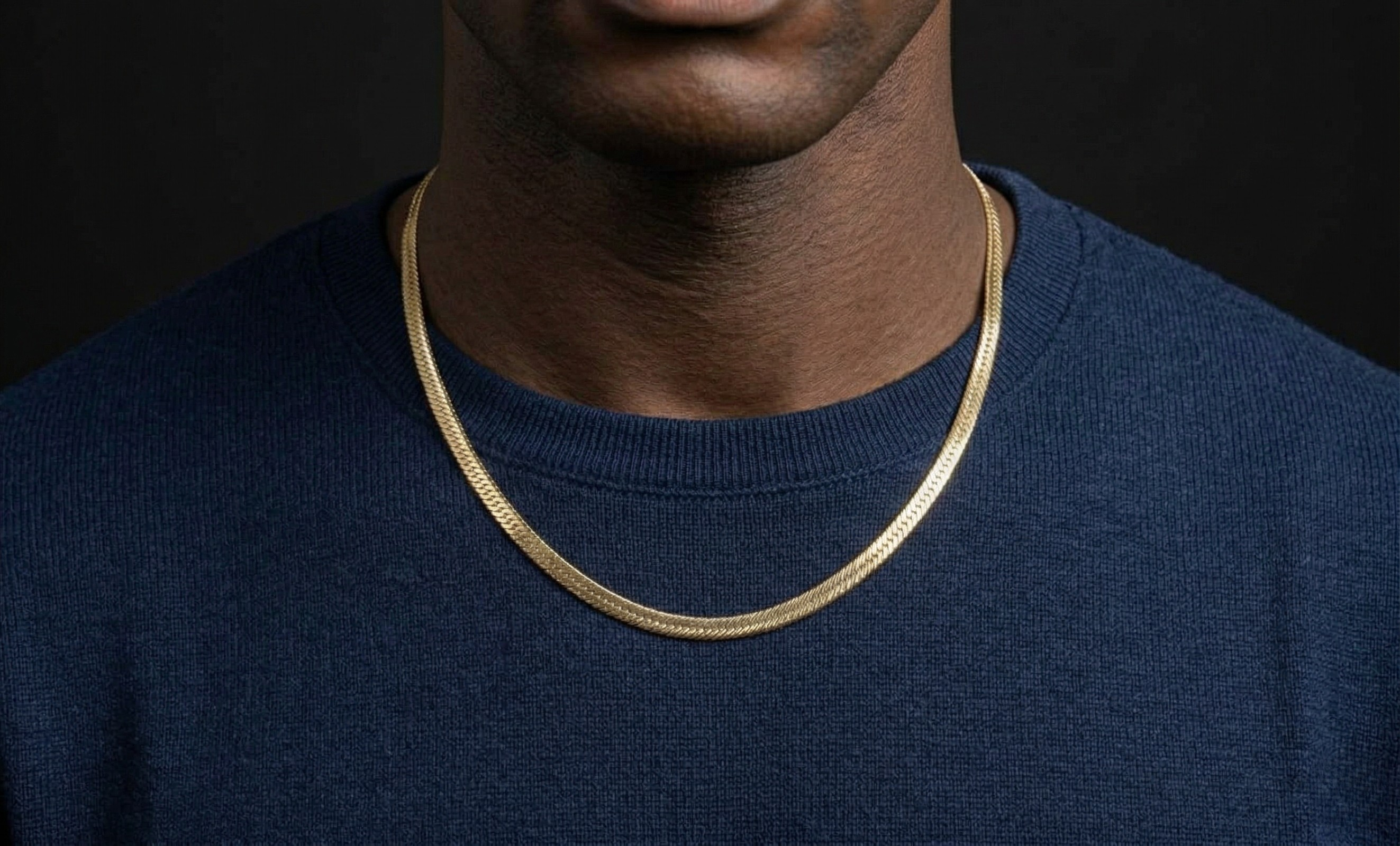 Person wearing a gold chain necklace against a black background-J.Collins Jewelry